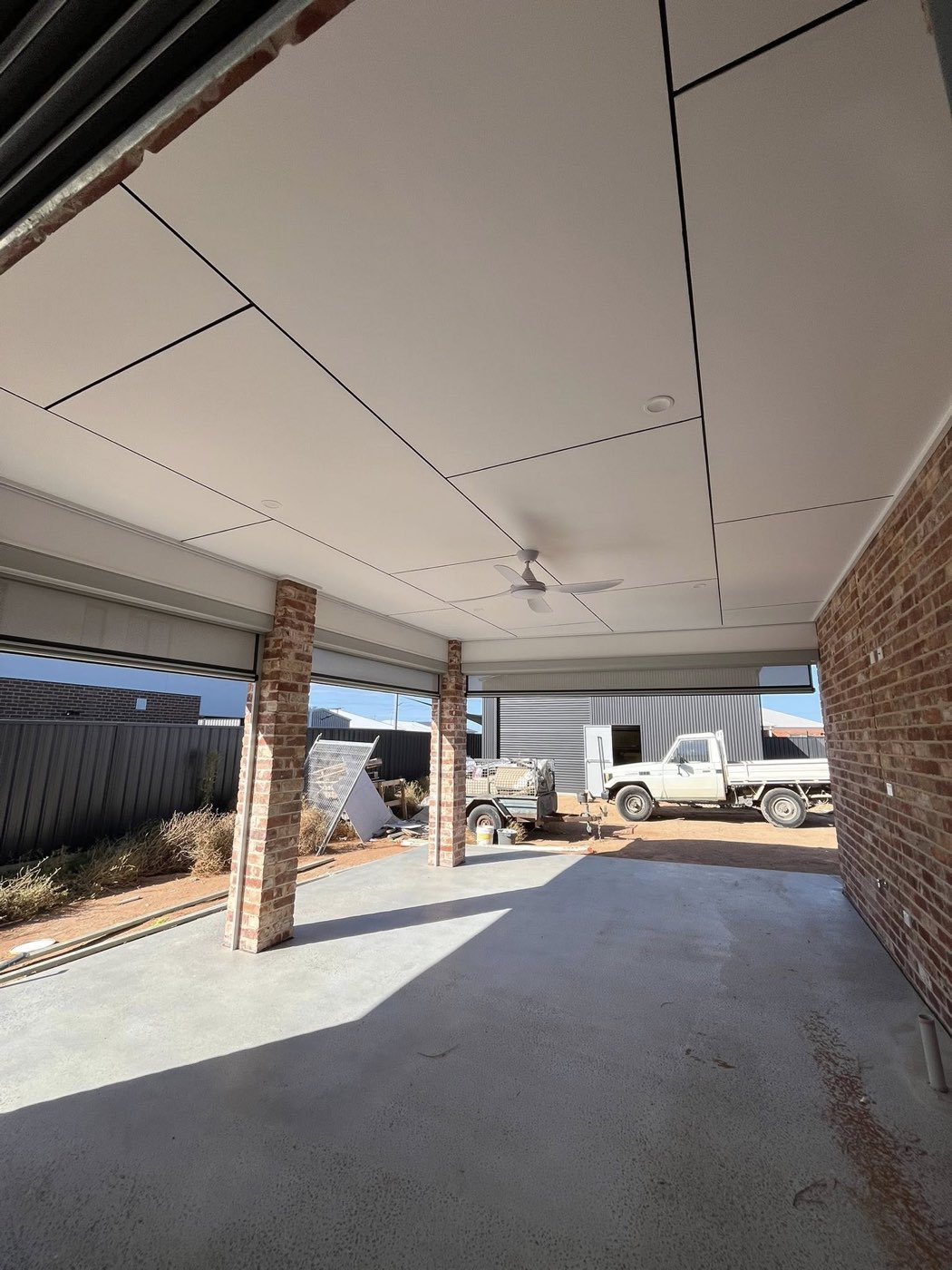Wide alfresco with brick pillars and concrete floor