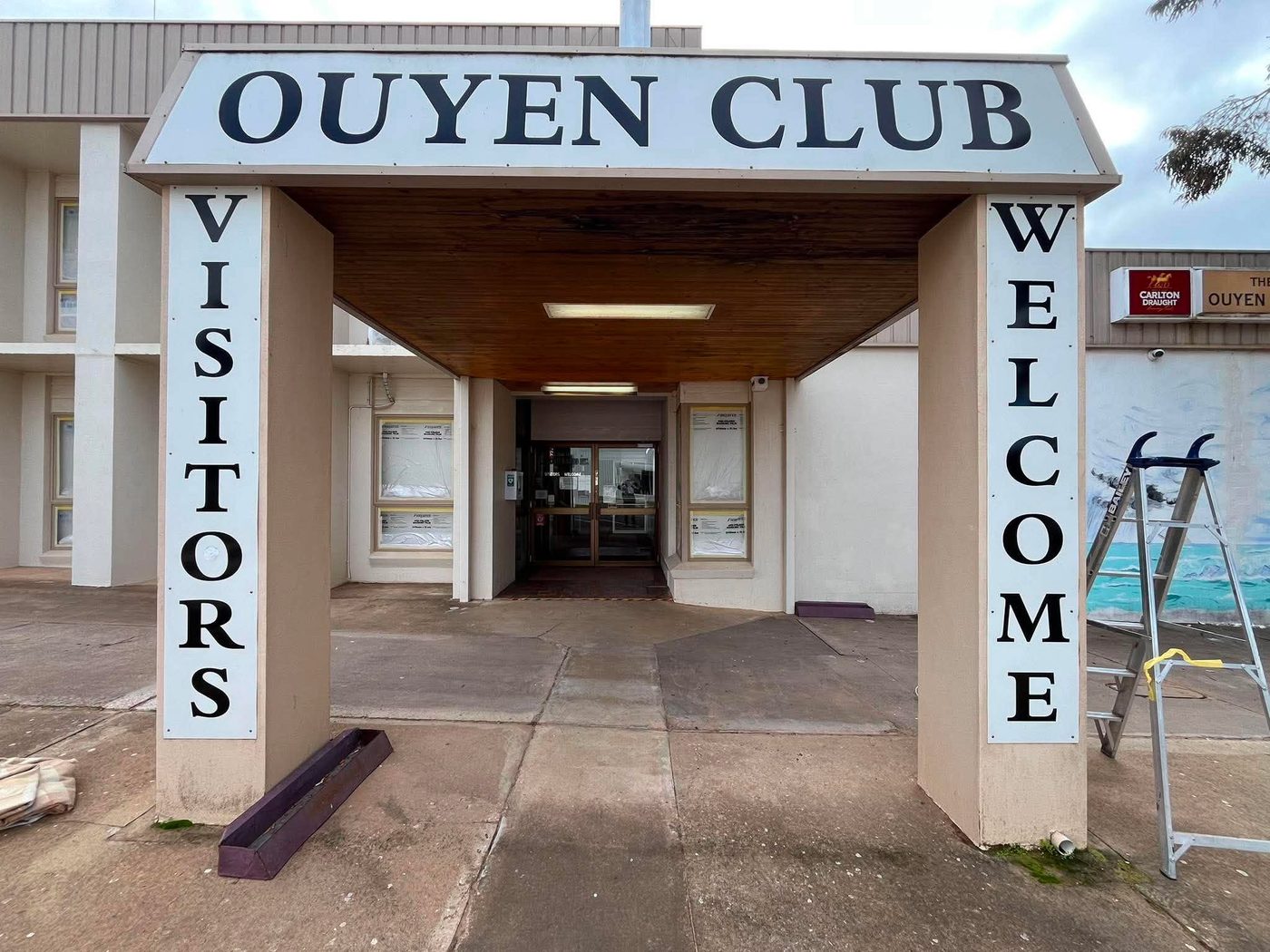 Ouyen Club visitor entrance before repaint — weathered timber soffit and beige columns